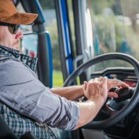 Caucasian Truck Driver in His 30s in the Semi Cabin. Modern Transportation Job.