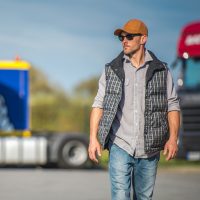 Caucasian Trucker in His 30s and the Truck Stop. Transportation Industry.